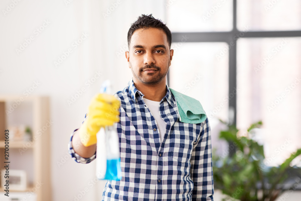 cleaning, housework and housekeeping concept - smiling indian man with detergent and rag on shoulder at home