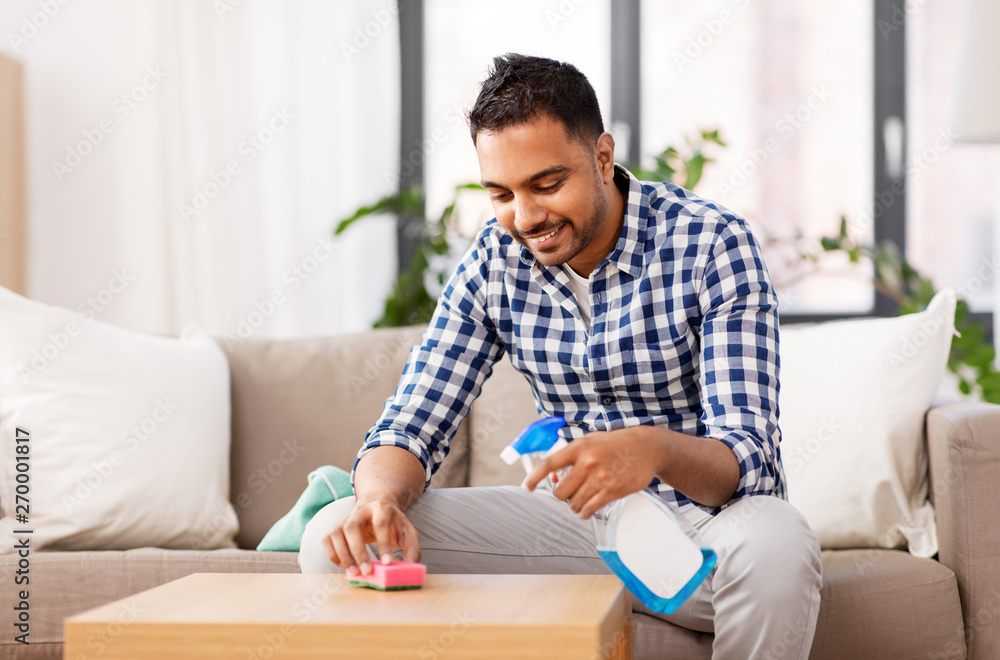 household and people concept - indian man cleaning table with detergent at home household and people concept - indian man cleaning table with detergent at home