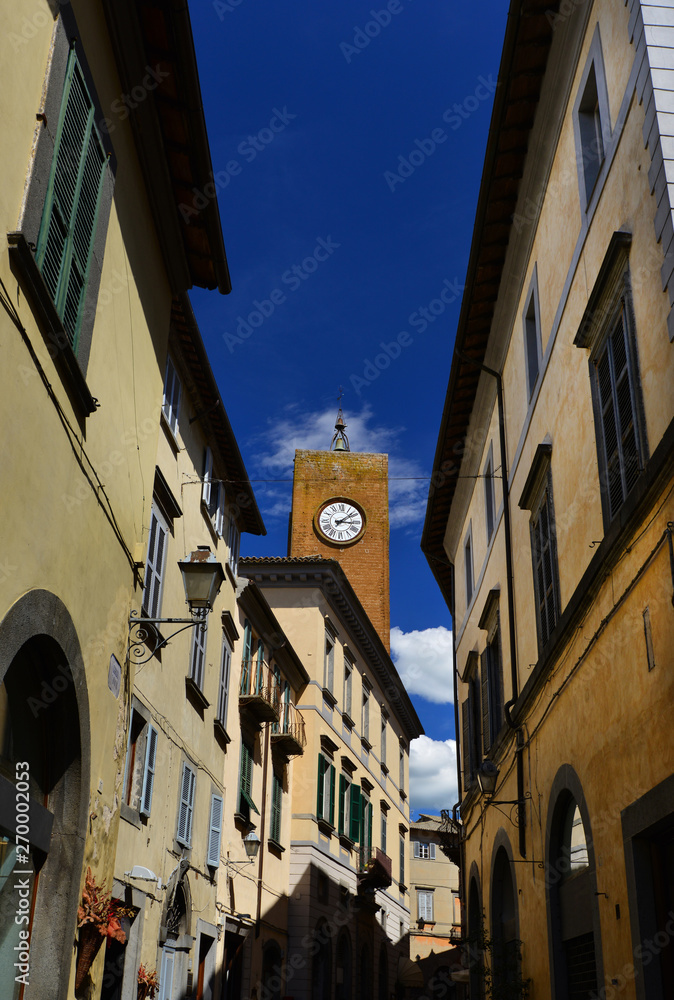 Medieval Torre del Moro (Moro Tower) with old clock, one of Orvieto landmarks seen from the city center narrow street