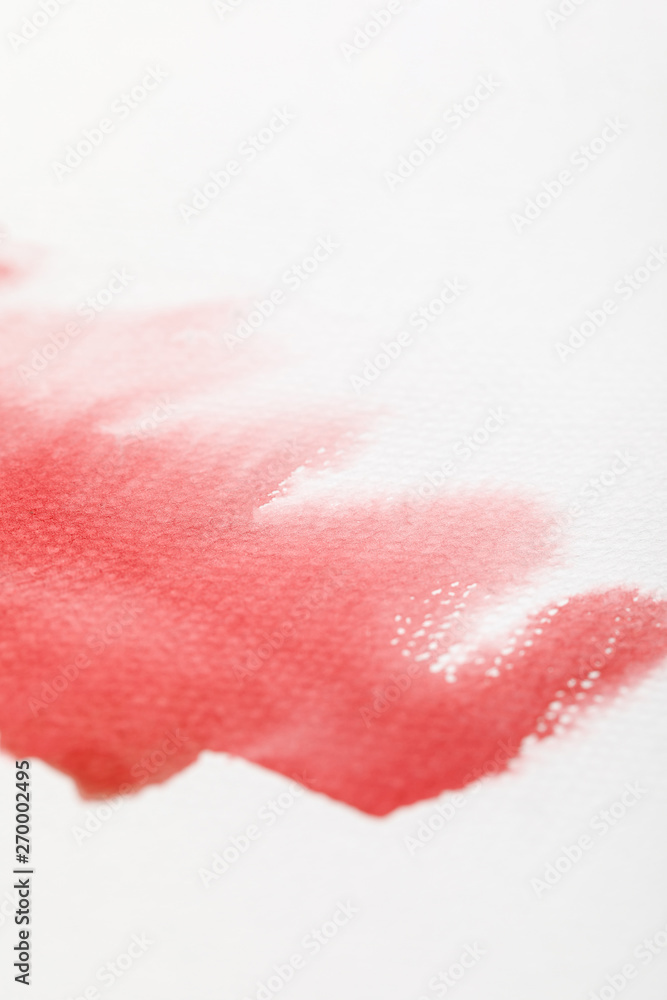 close up view of wet red watercolor paint spill on white background