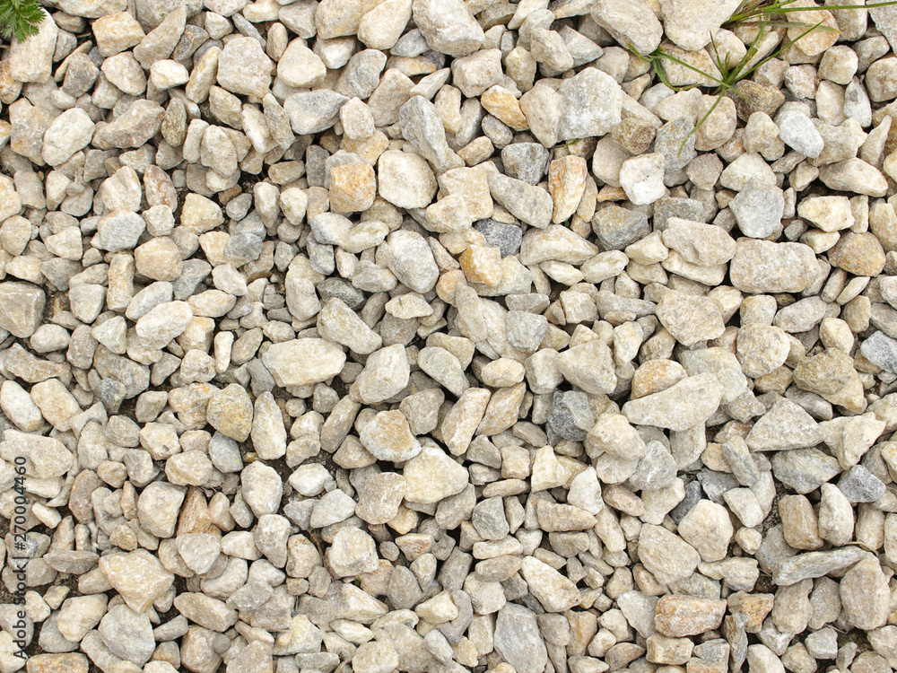 Fine and coarse gravel as background or texture with grass growing throu rocks Fine and coarse gravel as background or texture with grass growing throu rocks