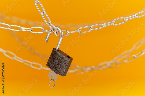 chain and open lock with key on orange background
