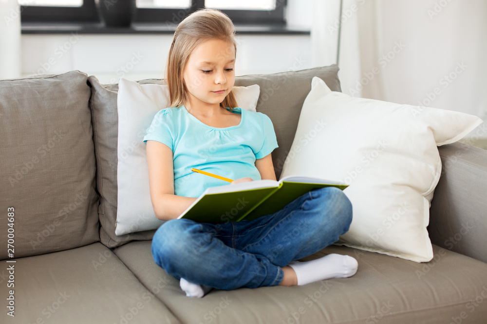 people, childhood and bedtime concept - little girl with diary and pencil sitting on sofa at home people, childhood and bedtime concept - little girl with diary and pencil sitting on sofa at home