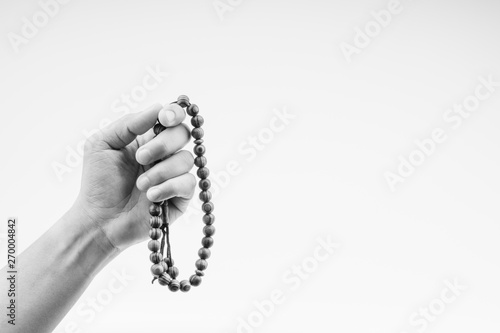 Hand holding a muslim rosary beads or Tasbih on black and white. Copy space and selective focus photo