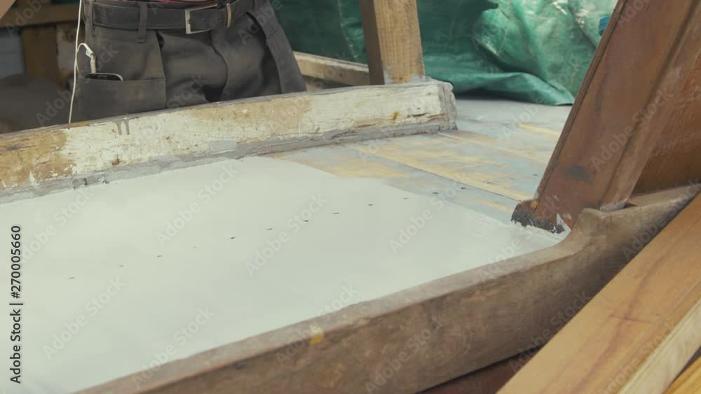 Young carpenter painting teak deck of old wooden boat with aluminium based protective primer. Young carpenter painting teak deck of old wooden boat with aluminium based protective primer.