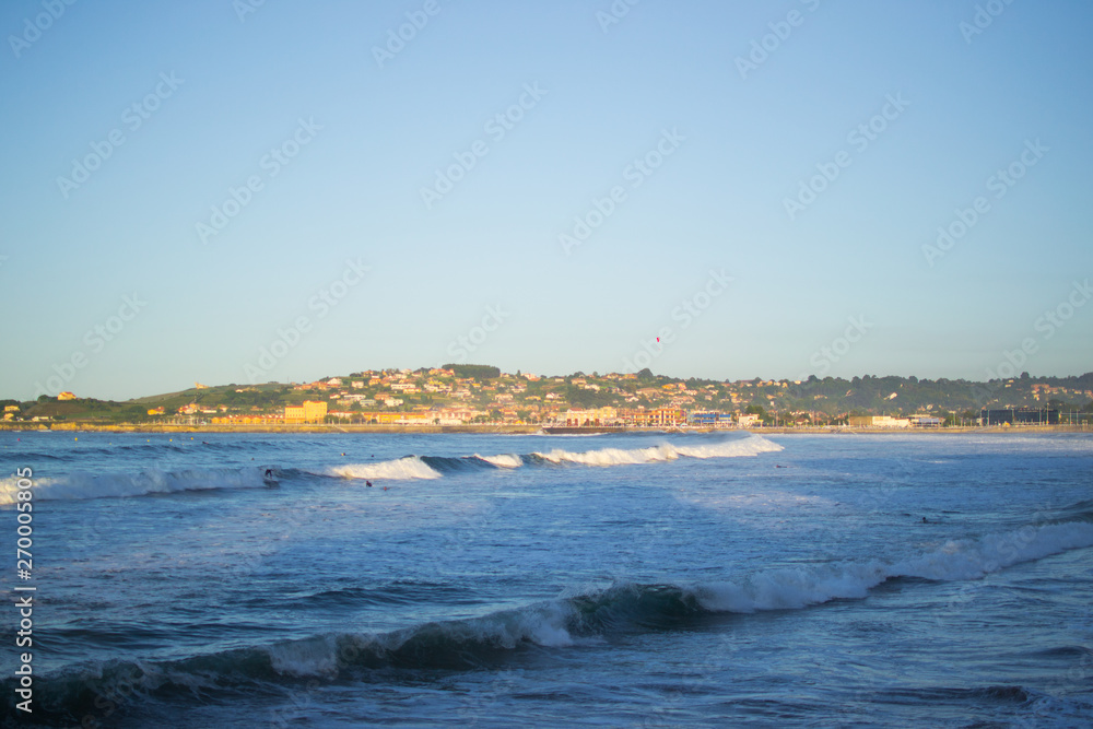 San Lorenzo beach and the Cantabrian Sea in Gijon, Asturias, Spain, with a green hill at the background
