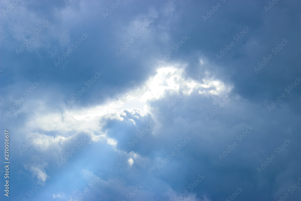  Breaking rays of sunlight through puffy clouds