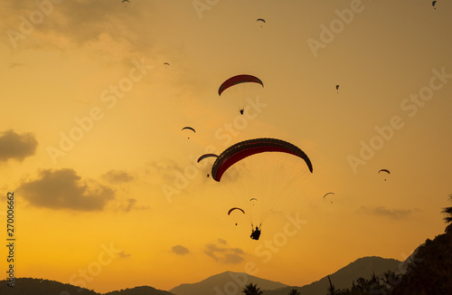 Silhouette paragliding. Sunset with dramatic sky. Summer background