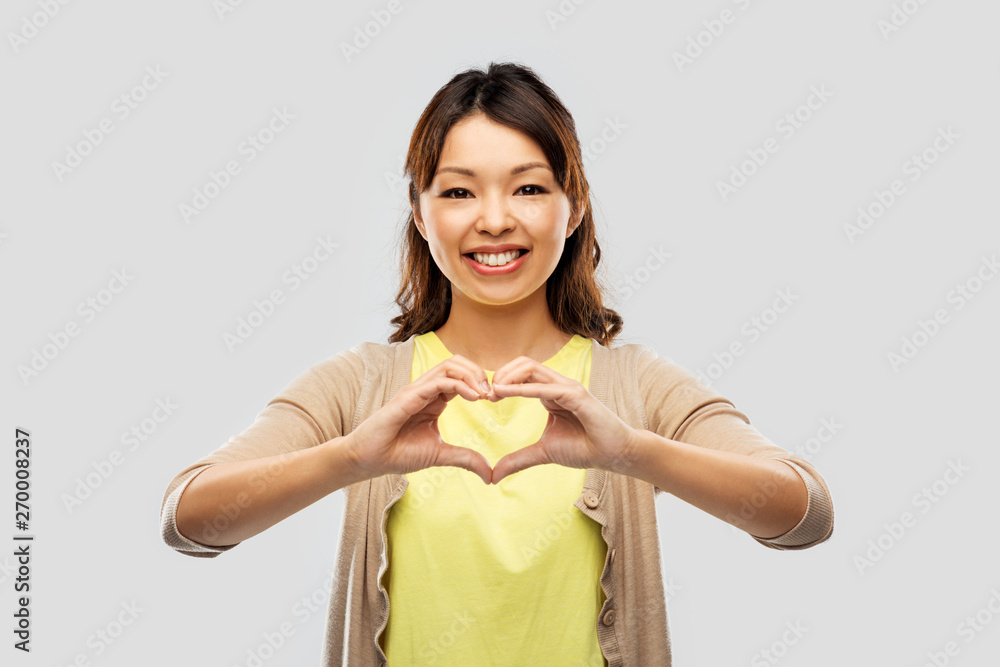 love and valentine's day concept - happy asian young woman making hand heart gesture over grey background love and valentine's day concept - happy asian young woman making hand heart gesture over grey background