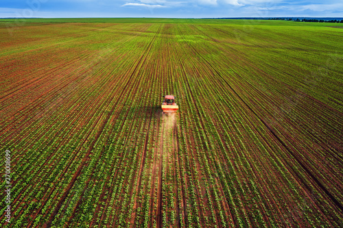 Tractor cultivating field at spring, aerial top drone view