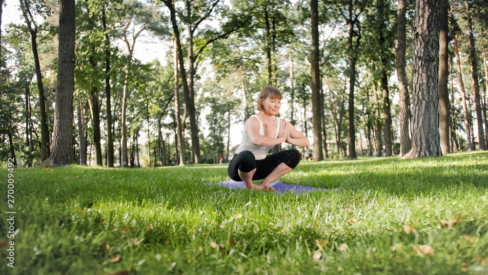 Photo of smiling woman doing yoga and fitness exercises. Middle aged people taking care of their health. Harmony of body and mind in nature Photo of smiling woman doing yoga and fitness exercises. Middle aged people taking care of their health. Harmony of body and mind in nature