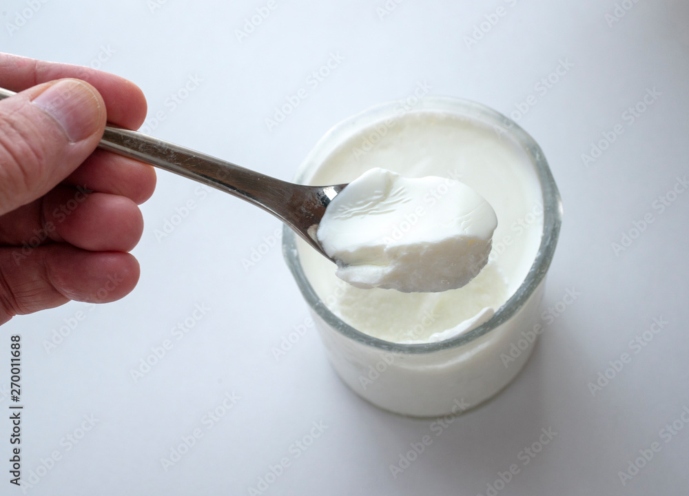 A hand holding/scooping yogurt from a glass. A hand holding/scooping yogurt from a glass.