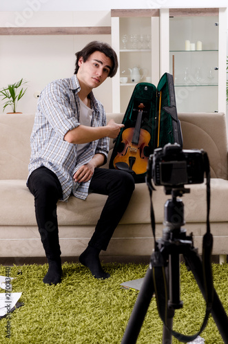Young male blogger playing violin at home  