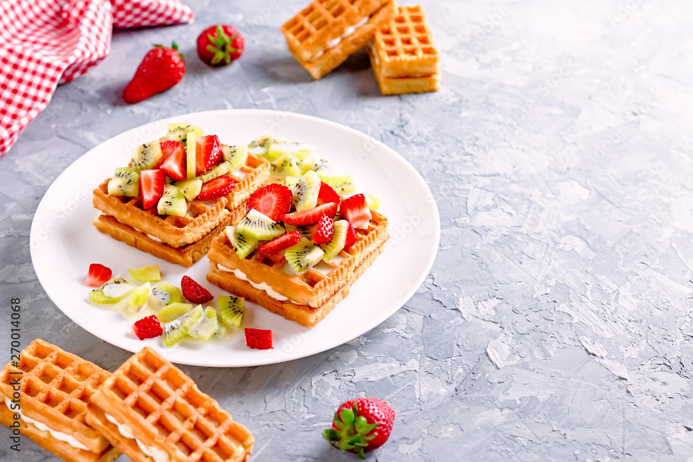 Belgian waffles with fruits strawberries and kiwi on white plate closeup. Tasty breakfast Belgian waffles with fruits strawberries and kiwi on white plate closeup. Tasty breakfast
