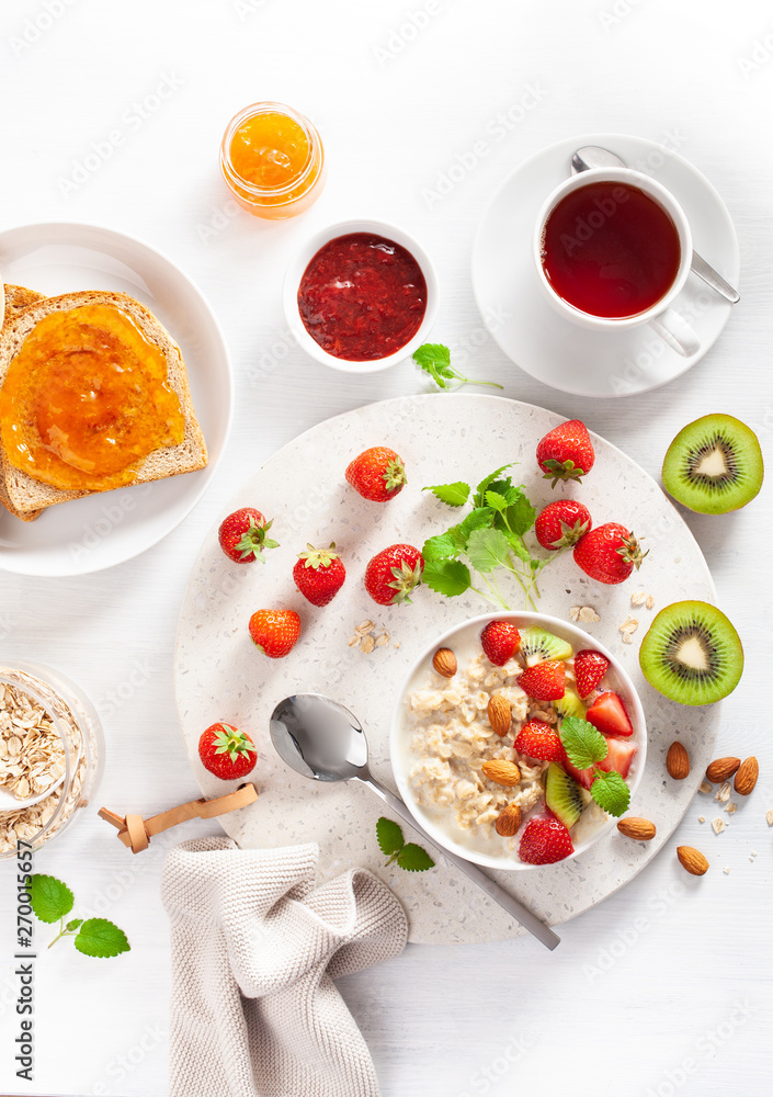 healthy breakfast with oatmeal porridge, strawberry, nuts, toast, jam and tea. Top view healthy breakfast with oatmeal porridge, strawberry, nuts, toast, jam and tea. Top view