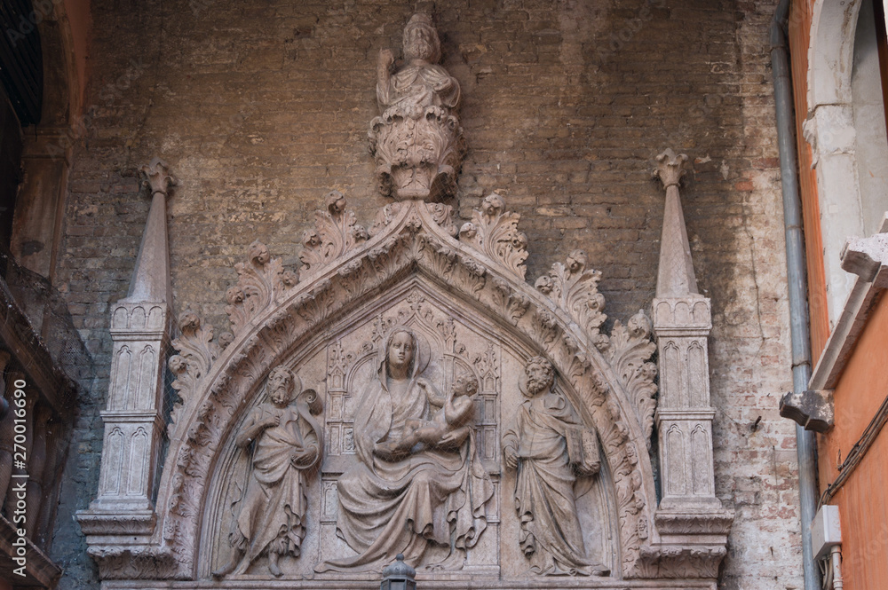 Stone sculpture of St Mary holding baby Jesus and two Apostles on her sides