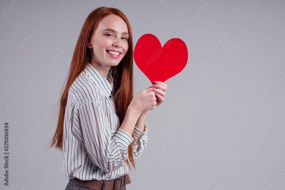 Happy redhead girl businesswoman in a striped shirt model sending air kiss with decorative hearts Valentines Day gift on white background studio Happy redhead girl businesswoman in a striped shirt model sending air kiss with decorative hearts Valentines Day gift on white background studio