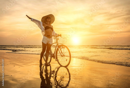 Happiness woman traveler with her bicycle walking on sea coastli photo