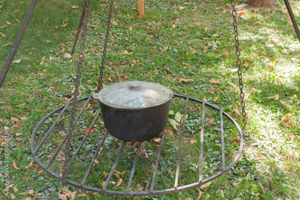 Outdoors cooking food in camping cauldron on barbecue grill nature green grass background summer sunny day. Outdoors cooking food in camping cauldron on barbecue grill nature green grass background summer sunny day.