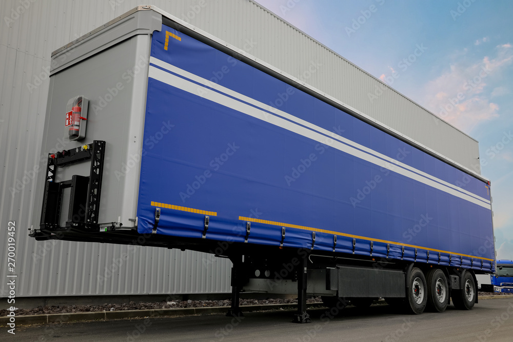 Semi remorque bleu triple essieux. Matériel de transport, remorques europe. Semi remorque européen stationné proche d'un dépôt de marchandises.