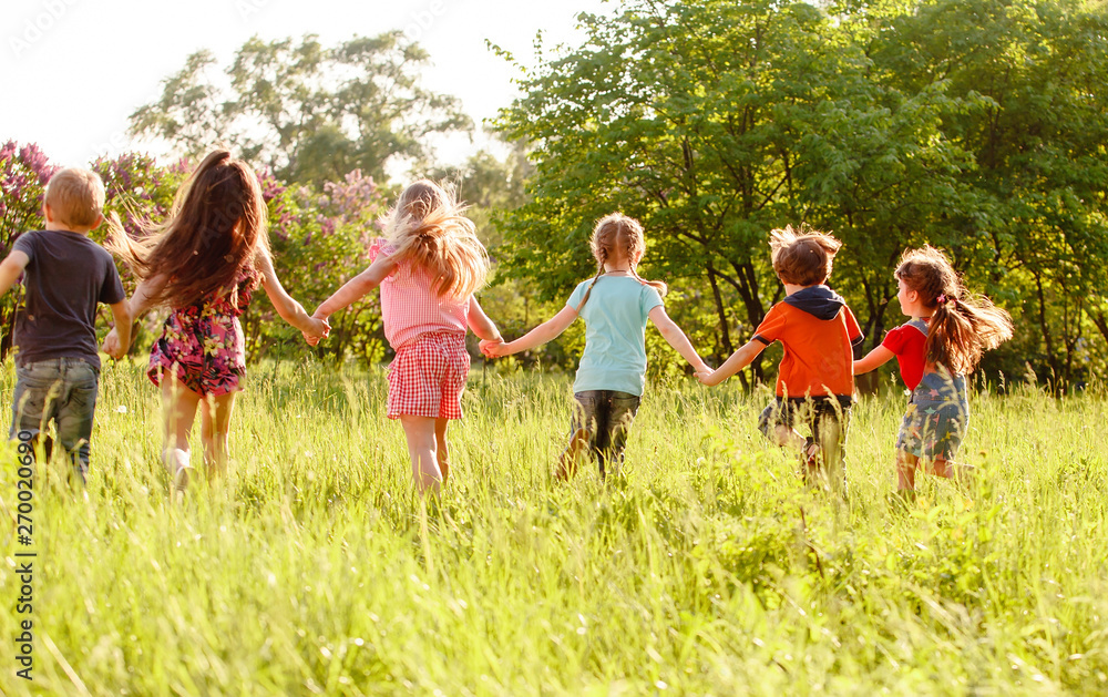Obraz premium a group of children playing and running in the park on a green gozon.