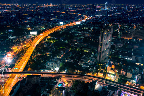 Aerial view of night modern city with light trails on the highway