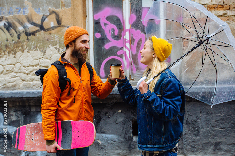 Ταπετσαρία Hipster beard man with longboard in his hand in orange hat and jacket drinks cof