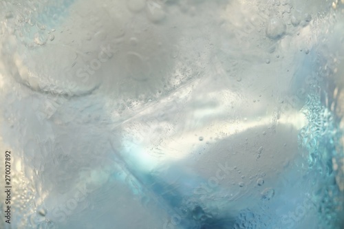 close-up ice cubes with blue water in drinking glass