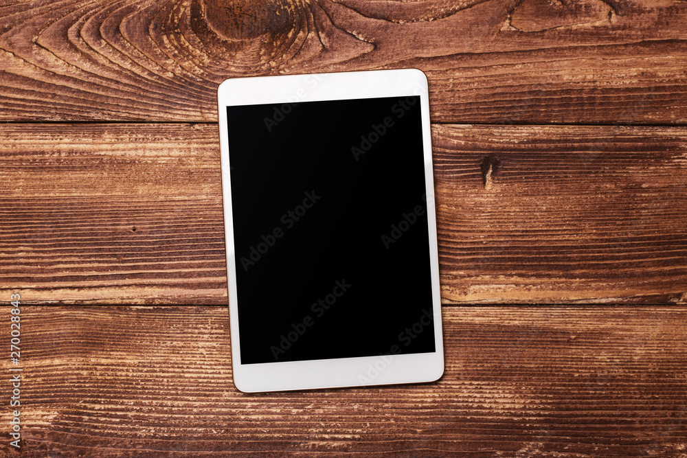 White digital tablet on wooden table. Top view with copy space. White digital tablet on wooden table. Top view with copy space.