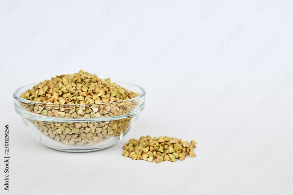 Green buckwheat untreated in a glass bowl for a healthy lifestyle on a white background. Green buckwheat untreated in a glass bowl for a healthy lifestyle on a white background.