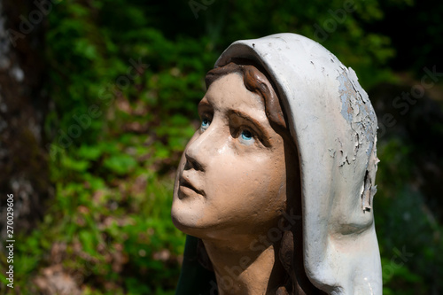 Statue of Bernadette Soubirous. Female worshipper and prayer is looking up the God or Virgin Mary. Woman and girl  is praying. Unfocused background. photo