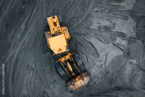 Yellow excavator or bulldozer in coal open cast mining quarry, industrial extraction of minerals, aerial top view photo
