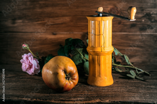 Rural still life with old coffee/pepper grinder and apple
