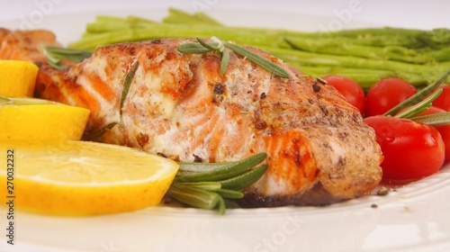 Grilled rosemary salmon served with asparagus, lemon, cherry tomatoes