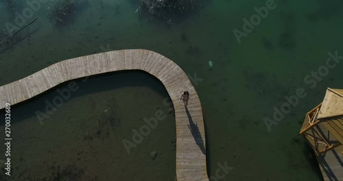 Aerial drone video on woman in swimsuit sunbathing on the pier. Female relaxing on vacations