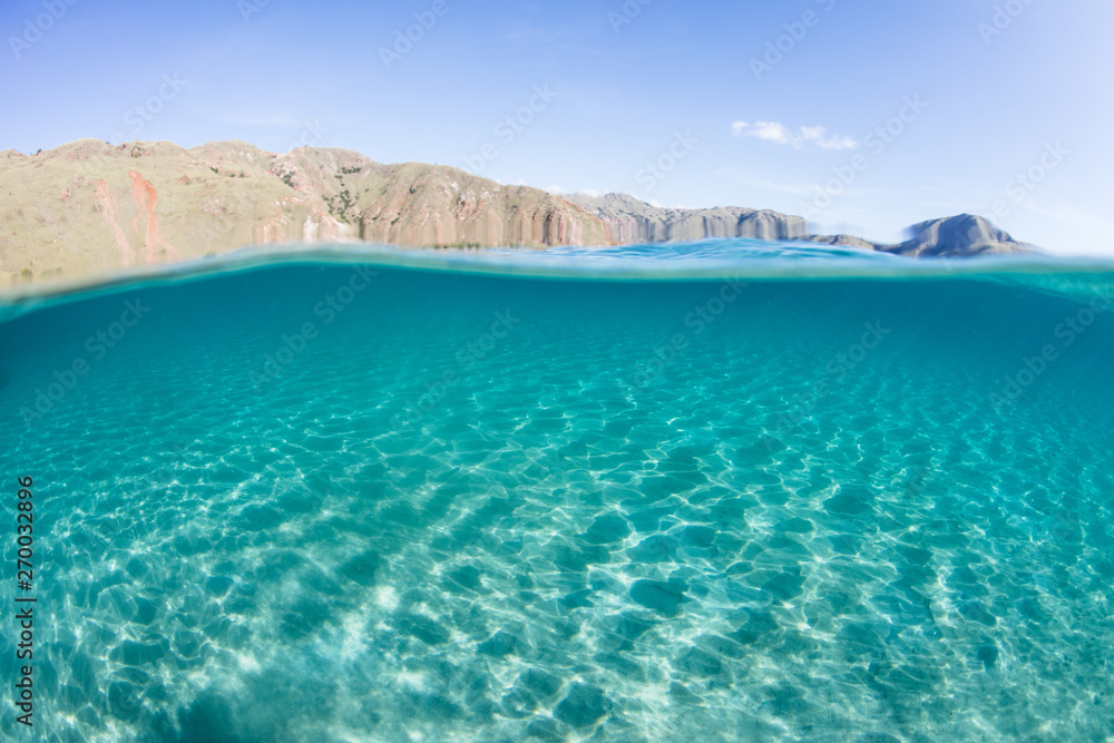 Bright sunlight ripples across a shallow, sandy seafloor near an island in Komodo National Park, Indonesia. This beautiful area is a popular destination for scuba diving and snorkeling. Bright sunlight ripples across a shallow, sandy seafloor near an island in Komodo National Park, Indonesia. This beautiful area is a popular destination for scuba diving and snorkeling.