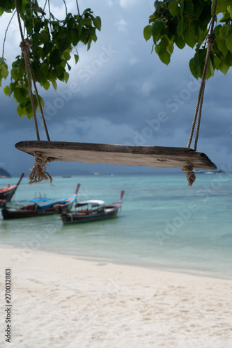 Fototapeta Naklejka Na Ścianę i Meble -  Swing hang from tree over beautiful tropical island view with boats on the sea and sky background. Exotic vacation on Amazing Koh Lipe in Thailand