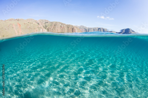 Bright sunlight ripples across a shallow  sandy seafloor near an island in Komodo National Park  Indonesia. This beautiful area is a popular destination for scuba diving and snorkeling.