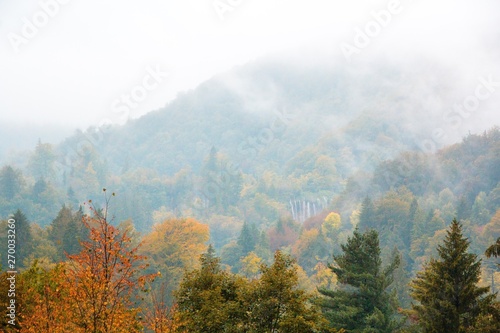 Plitvice lakes national Park, Croatia. Autumn landscape. Golden trees, fog, mountains and waterfall.