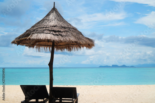 Fototapeta Naklejka Na Ścianę i Meble -  Amazing tropical beach with deckchairs, umbrella over lagoon sea and sky background. Tropical vacation, holiday, travel concept
