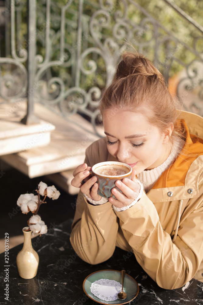 Young woman enjoying tasty coffee at table outdoors Young woman enjoying tasty coffee at table outdoors