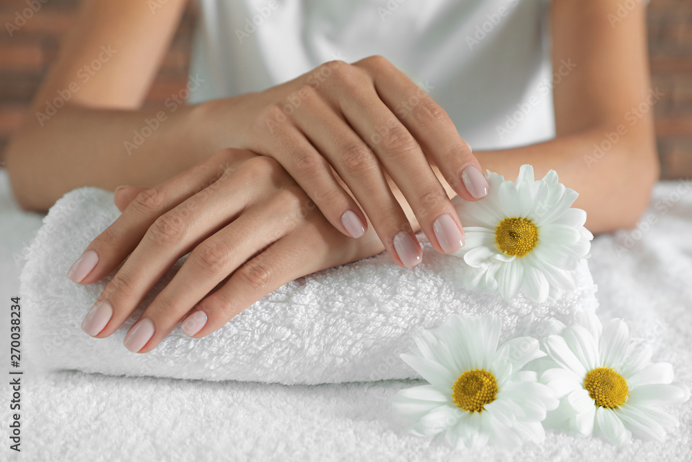 Woman with smooth hands and flowers on towel, closeup. Spa treatment