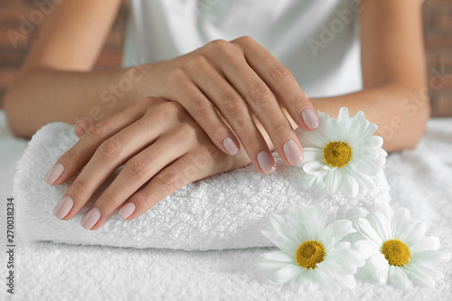 Woman with smooth hands and flowers on towel  closeup. Spa treatment