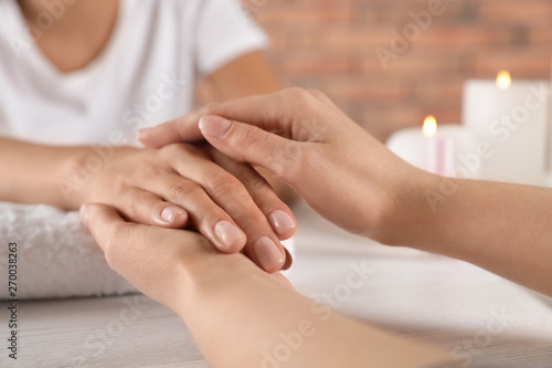 Cosmetologist massaging woman s hand at table in spa salon  closeup