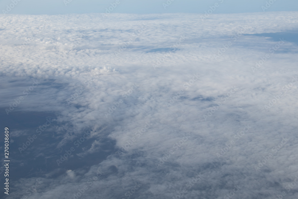 Aerial view from plane window with blue sky and white clouds