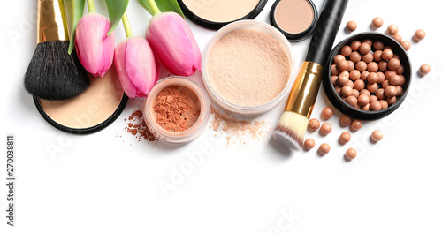 Many different makeup products and spring flowers on white background, top view