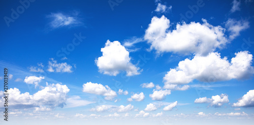 Beautiful blue sky background with sparced white clouds. Panorama