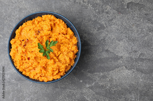 Bowl with mashed sweet potatoes on grey background, top view. Space for text