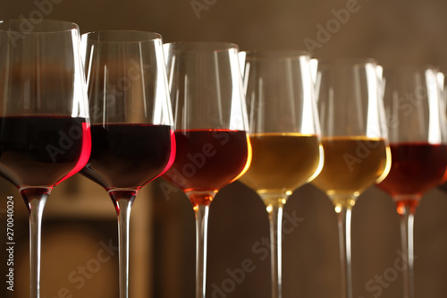 Glasses of different wines against blurred background, closeup. Expensive collection