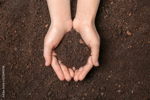 Woman holding pile of soil above ground, top view
